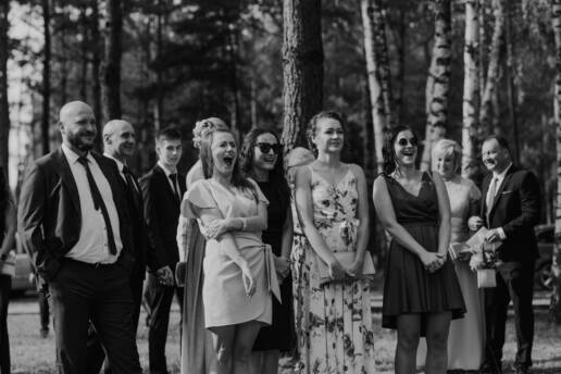 Fotografia z dnia ślubu w Katowicach, rozbawieni goście weselni głośno wiwatują podczas pocałunku pary młodej